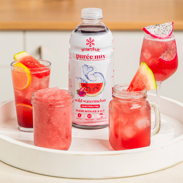 A white bottle of Smartfruit Wild Watermelon Puree with a glass of pink liquid and a slice of watermelon.