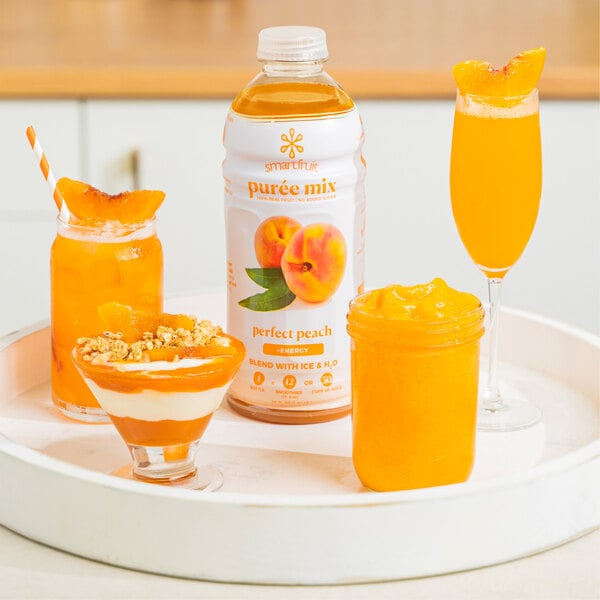 A table with a glass of orange yogurt and a jar of Smartfruit Perfect Peach Puree juice.