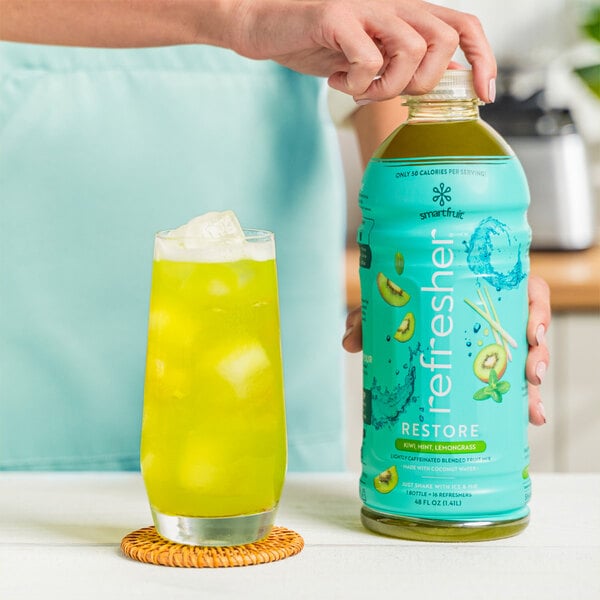A person holding a bottle of Smartfruit Kiwi / Mint / Lemongrass Refresher.