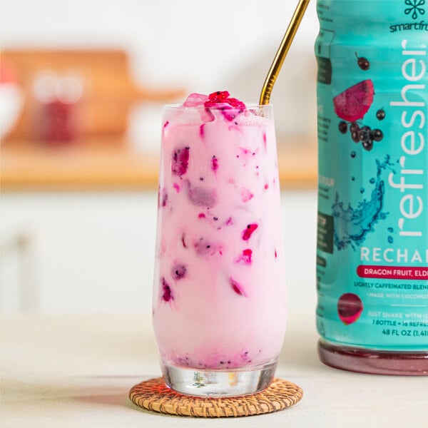 A glass of pink Smartfruit Recharge Dragon Fruit and Elderberry beverage with a straw.