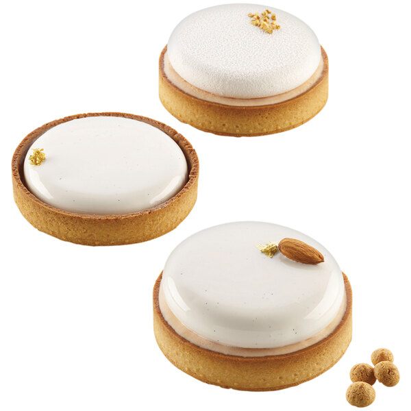 Three small round tarts with white frosting and almonds.