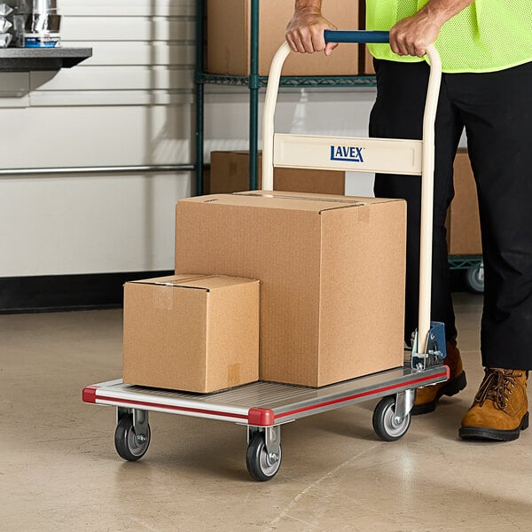 A person pushing a Lavex aluminum platform truck with boxes on it.