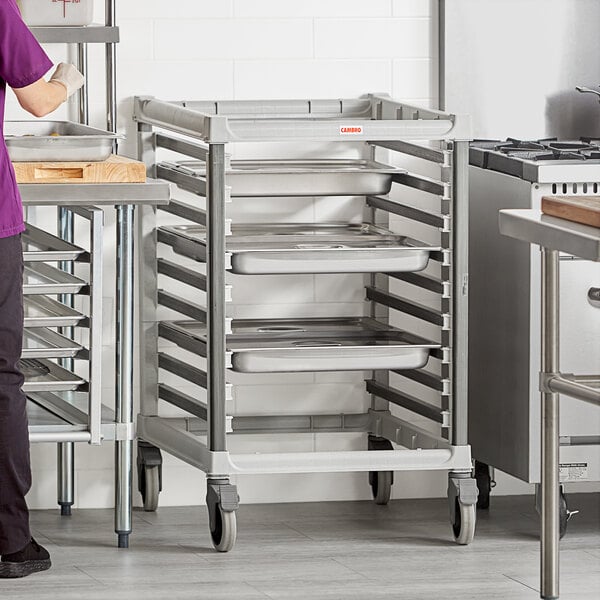 A woman assembling a Cambro Camshelving trolley with metal trays.