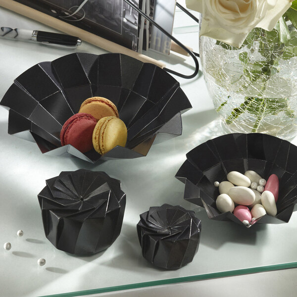 A table with three black Solia Iris bowls filled with macarons.