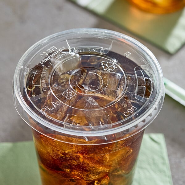 A clear plastic flat lid with a straw slot on a cup filled with iced beverage.