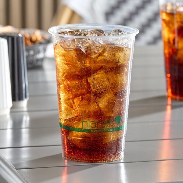 A clear 20 oz. compostable plastic cold cup filled with iced soda.