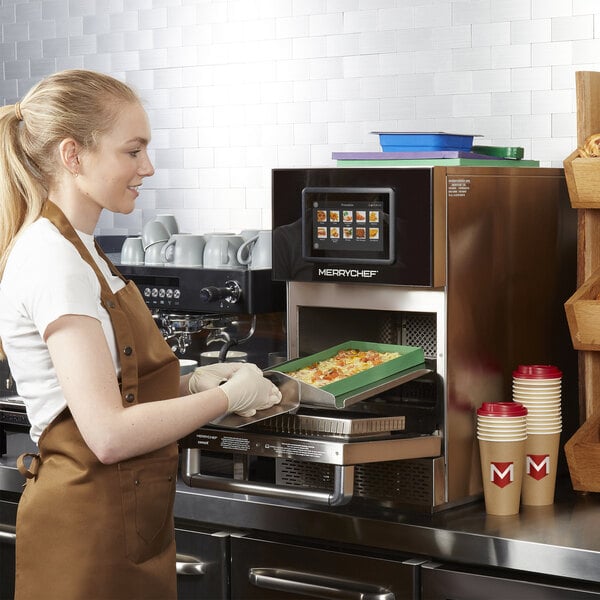 A stainless steel Merrychef conneX12 high-speed oven being used in a commercial kitchen setting.