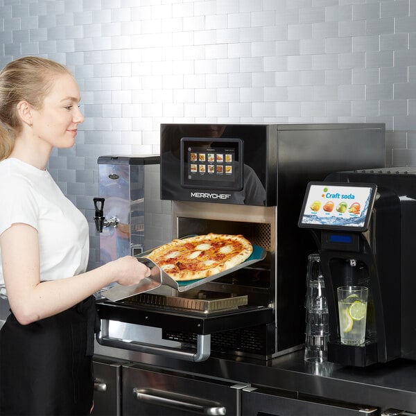 A Merrychef conneX12 high-speed oven in carbon black finish being used to bake a pizza.