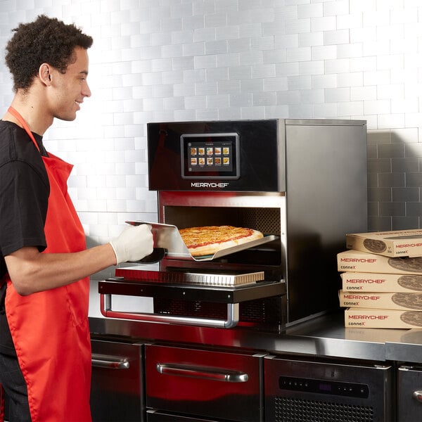 A Merrychef conneX16 high-speed oven with a stainless steel finish being used to bake a pizza.