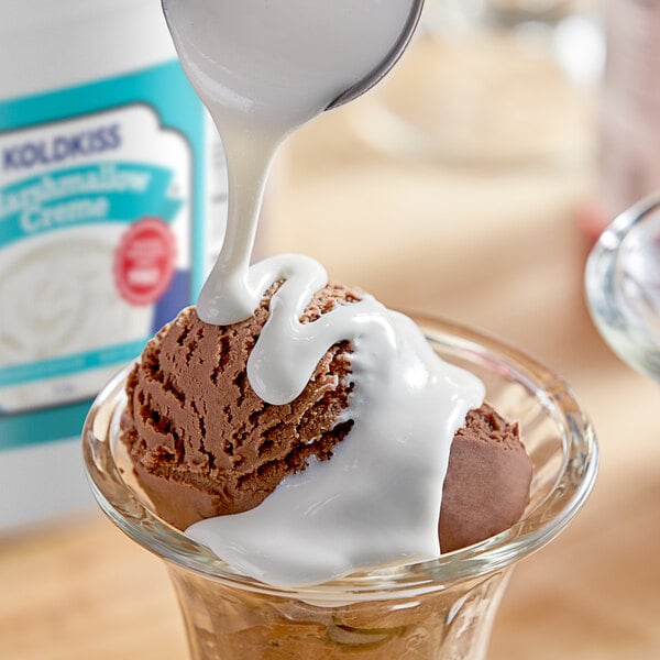 A spoon pouring Koldkiss Marshmallow Creme onto a scoop of ice cream.