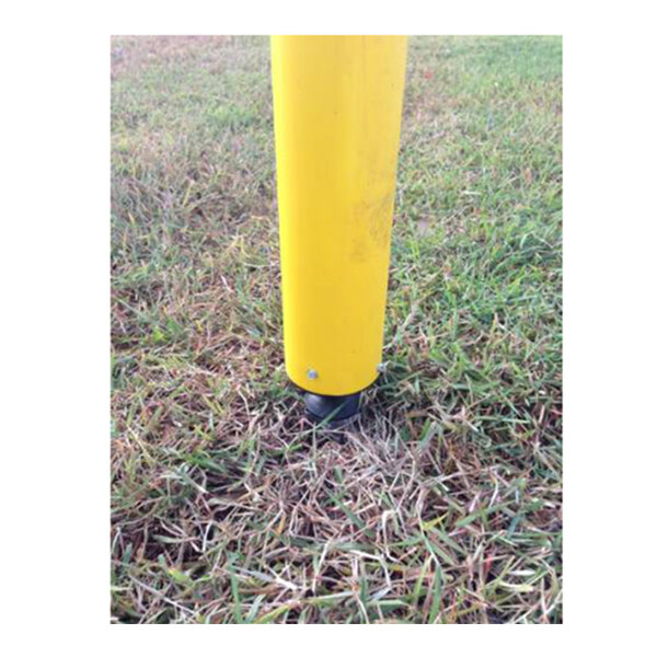 An Impact Recovery Systems yellow pole with a black base in grass.