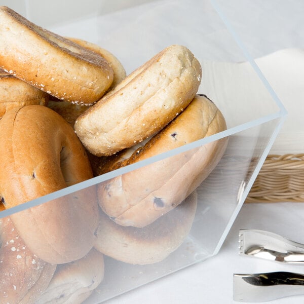 A clear plastic Cal-Mil food bin filled with bagels.