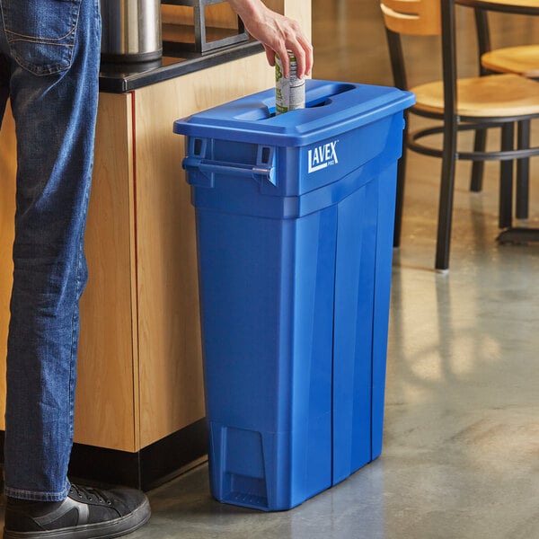 A man standing next to a Lavex Pro blue rectangular recycling bin with a blue mixed recycling lid.