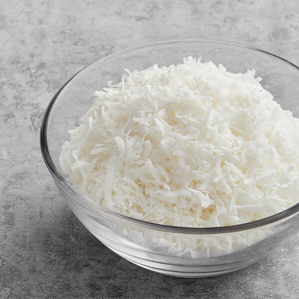 A bowl of Unsweetened Coconut Flakes on a gray surface.