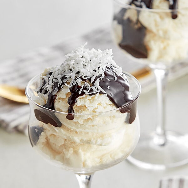 A glass of ice cream with chocolate sauce and coconut chips.