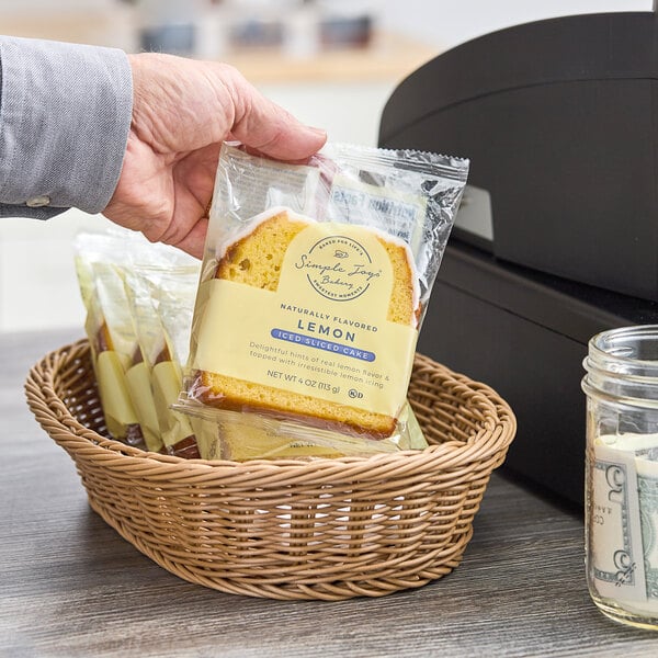 A hand holding a bag of Simple Joys Iced Lemon Cake slices.