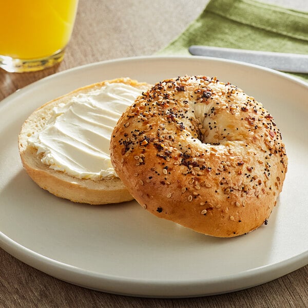A Just Bagels everything bagel with cream cheese on a plate.