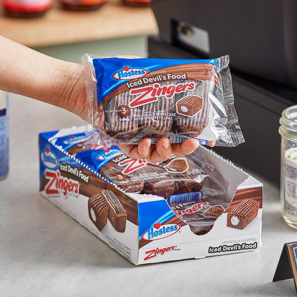 A hand holding a package of Hostess Zingers Devil's Food Cake.