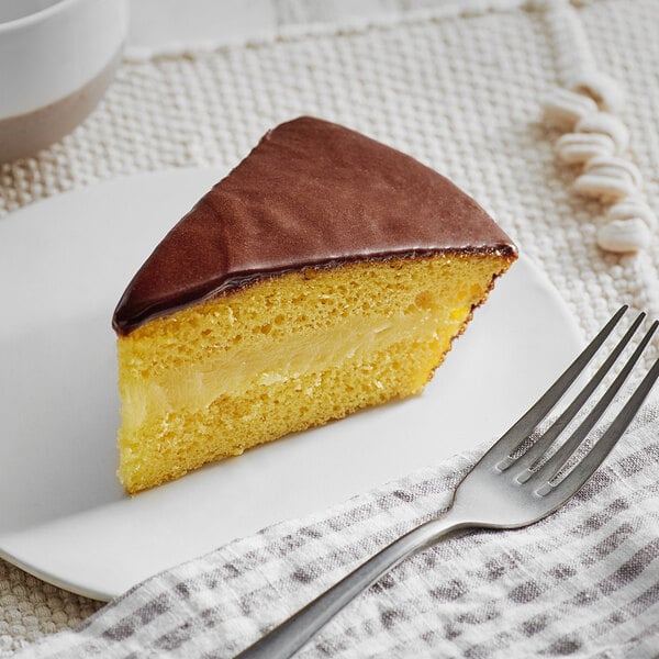 A slice of Chef Pierre Boston Cream Pie with chocolate frosting on a plate.