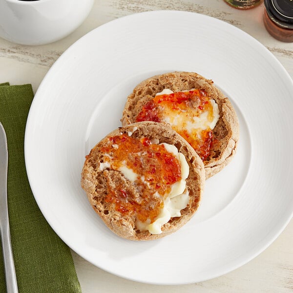 Two Thomas' Whole Wheat English Muffins with cheese and jam on a white plate.