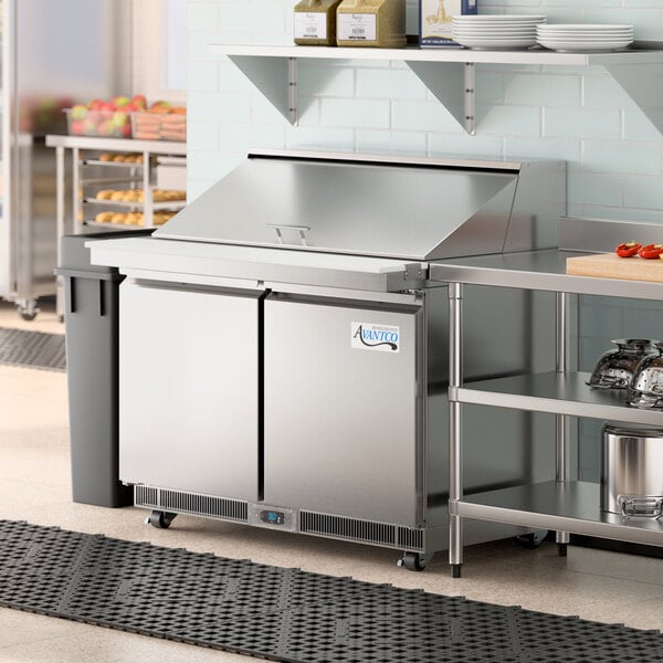 An Avantco sandwich prep table on a stainless steel counter in a commercial kitchen.