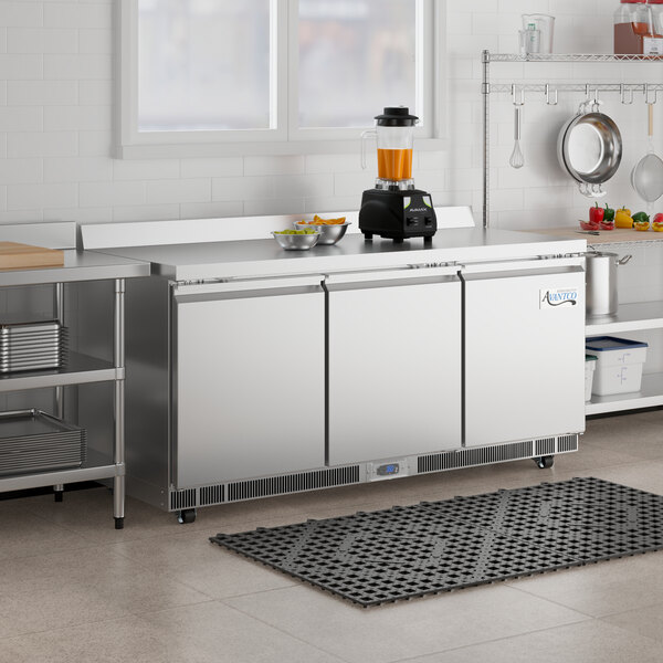 An Avantco worktop refrigerator on a stainless steel counter in a professional kitchen.