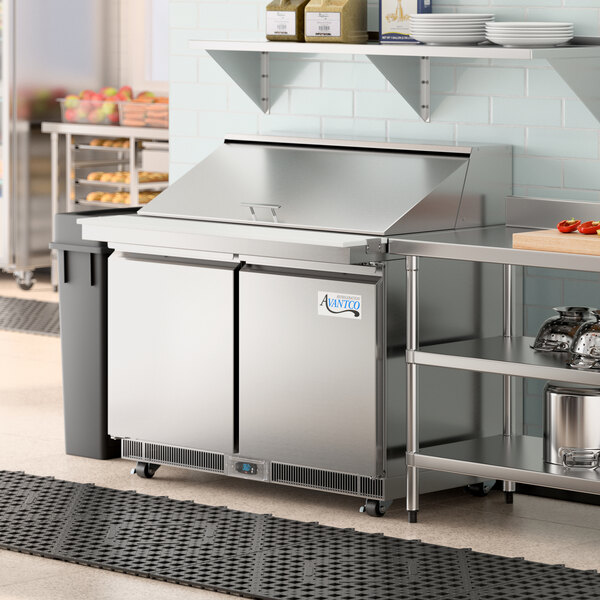 An Avantco stainless steel sandwich prep table with shelves holding food.