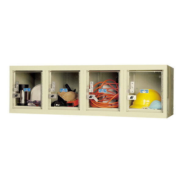 A tan wall mount box locker with four tiers holding various items.