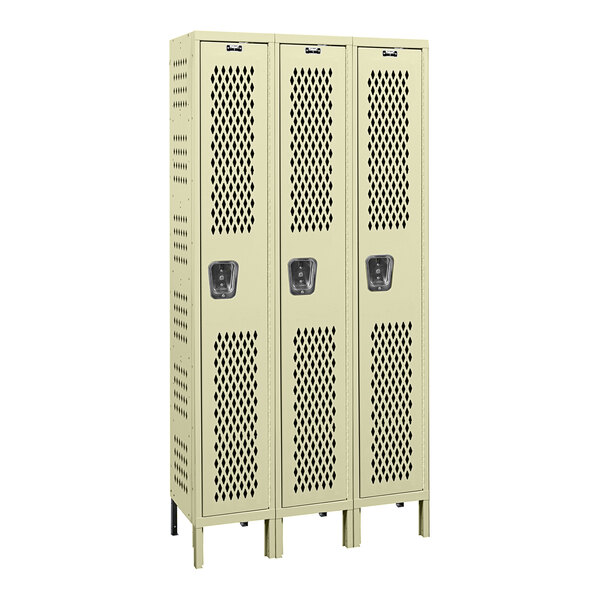 A close-up of a group of tan Hallowell ventilated lockers with holes in them.