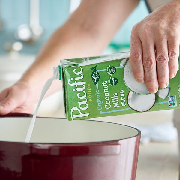 A carton of Pacific Foods Organic Coconut Milk being poured into a pot.