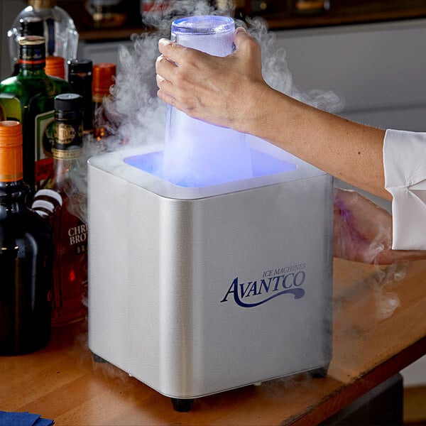A person using an Avantco countertop glass froster on a counter in a cocktail bar.