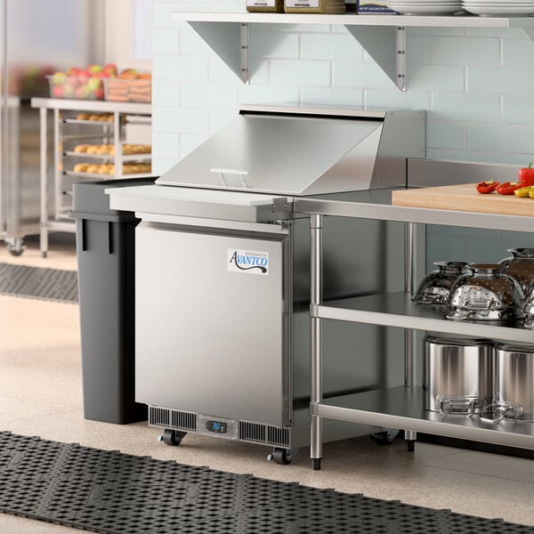 An Avantco refrigerated sandwich prep table on a stainless steel counter in a commercial kitchen.