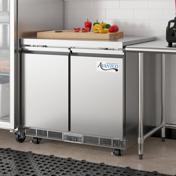 An Avantco stainless steel undercounter freezer with a cutting board on top.