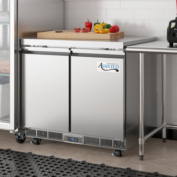 An Avantco stainless steel undercounter refrigerator with a cutting board on top.