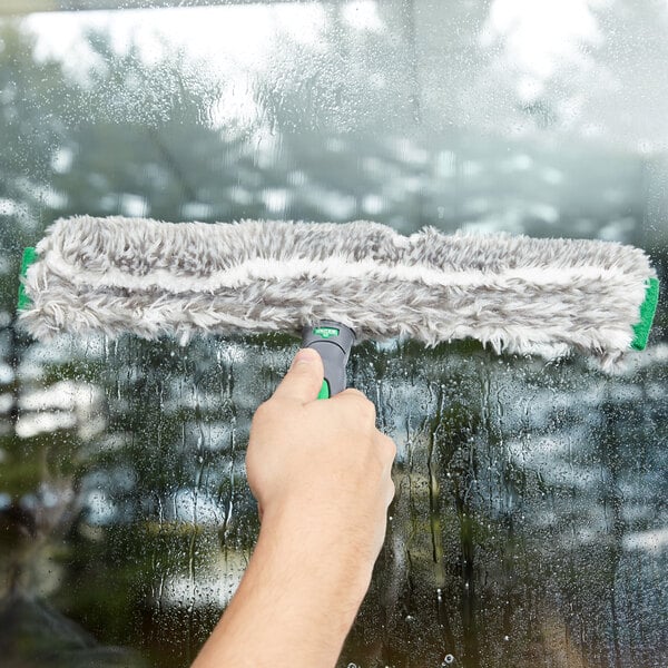 A hand using Unger ErgoTec StripWasher to clean a window.