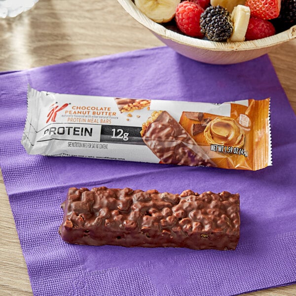 A Kellogg's Special K chocolate peanut butter protein meal bar with nuts next to a bowl of fruit.