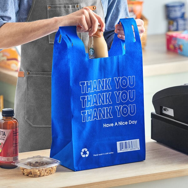 A man holding a blue Inteplast Group reusable T-shirt bag with a bottle of milk in it.