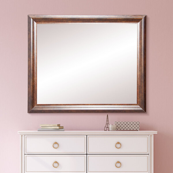 A BrandtWorks copper brown mirror on a white dresser.