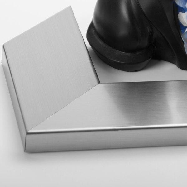 A close-up of a BrandtWorks stainless steel mirror in a metal corner.