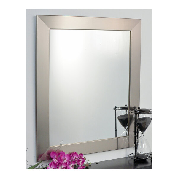 A BrandtWorks stainless steel mirror with purple flowers reflected in it.