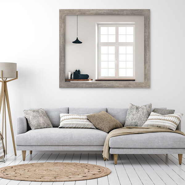 A BrandtWorks Barnwood Gray Finish mirror hanging above a white couch.
