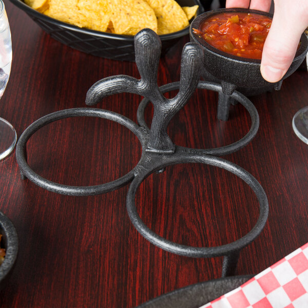 A person using an HS Inc. salsa caddy to hold molcajetes of salsa on a table.