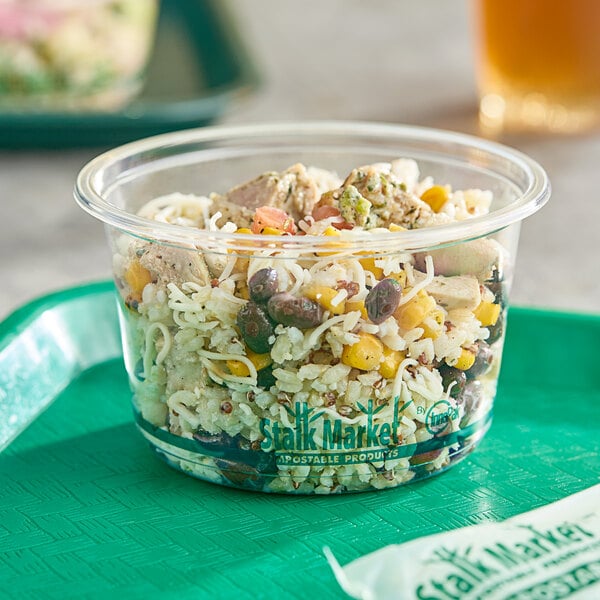 A Stalk Market clear plastic deli container filled with food on a table.