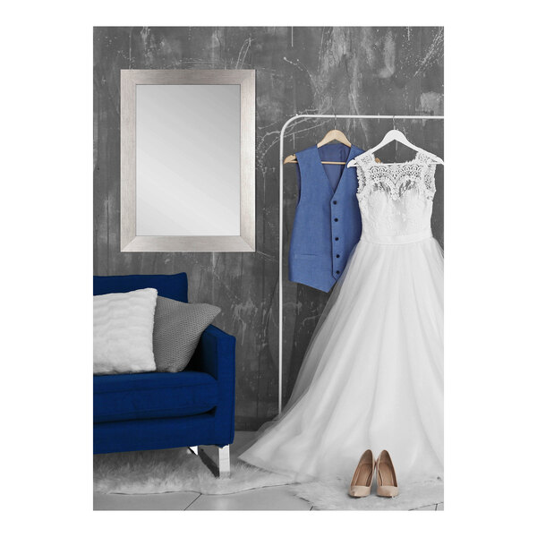 A wedding dress hanging next to a BrandtWorks silver grain finish mirror.
