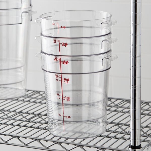 A wire rack of three Cambro clear plastic food storage containers.