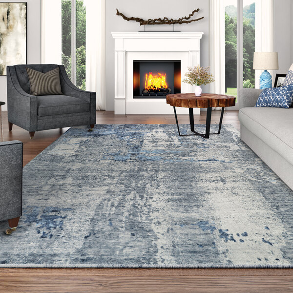 A modern living room with a Couristan Dreamscape Odyssey gray and blue rug under a wood table in front of a fireplace.