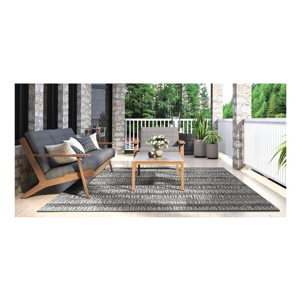 A table and chairs on a Couristan Tangent area rug on a porch.
