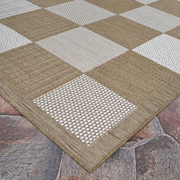 A Couristan light brown and ivory checkered area rug on a stone floor.