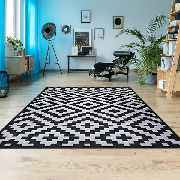 A Couristan Afuera Diatomic area rug in a white and black room.