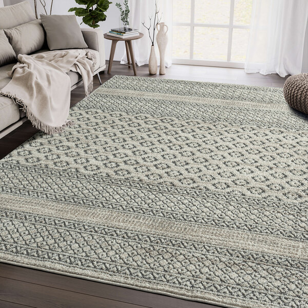 A cream and gray geometric lined Abani Cabo Collection area rug on the floor.
